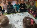 Dzieci siedzą w kole, na środku plakat z prawami dziecka