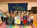 Grupa dzieci stoi na tle kolorowego napisu Dzień Tolerancji