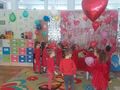 dzieci na tle fotościanki z napisem walentynki tańczą z balonami