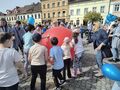 dzieci na Rynku przetaczają dużą czerwoną piłkę