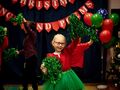 Dziewczynka tańczy i uśmiecha się.W tle dzieci tańczą z pomponami