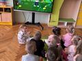 dzieci w sali przedszkolnej oglądają film edukacyjny