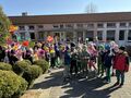 dzieci przed przedszkolem z kolorowymi kwiatami i wiatrakami