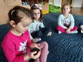 Trzy dziewczynki na dywanie, jedna trzyma węgiel.