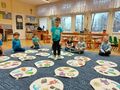 Dzieci ubrane na niebiesko siedzą wokół dobble xxl rozłożonym na dywanie