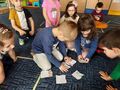 Pięcioro dzieci na dywanie układa puzzle mapy Polski.
