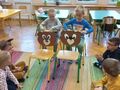 dzieci siedza na dywanie siedzą za sylwetami misiów i nawijają nitkę