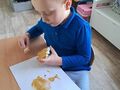 dziecko przy stoliku maluje brązową farbą gipsowego misia