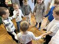 sala przedszkola zdjęcie z góry dzieci stoją w kole i trzymają się za ręce