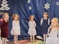 w tle dziewczynki na pierwszym planie dziewczynka ubrana na biało trzyma mikrofon