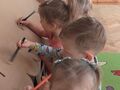 Dzieci kolorują duży domek z kartonu. 