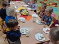 dzieci degustują owoce i kanapki z rzodkiewką papryką
