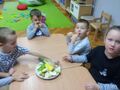 dzieci przy stoliku zjadają pokrojone owoce