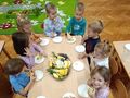 sala przedszkolna dzieci przy stoliku spożywają przygotowane owoce
