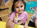 sala przedszkolna uśmiechnięta dziewczynka pokazuje owocowy szaszłyk