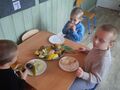 troje chłopców degustuje owoce przy stoliku