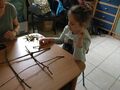 Dziewczynka gra przy stoliku z panią w "kółko i krzyżyk" wykonane z gałązek i kartonowych kółek. 