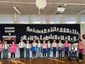 Grupa dzieci stoi na tle dekoracji w sali przedszkolnej