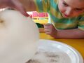 Dziewczynka trzyma balon obserwuje co dzieje się z solą i pieprzem na talerzu