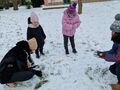 Dzieci wraz z paniami lepią bałwana