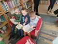 Trzej chłopcy siedzą na małej kanapie i oglądają książki.
