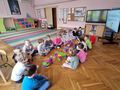 dzieci siedzą w dwóch rzędach. pomiędzy nimi budowle z klocków