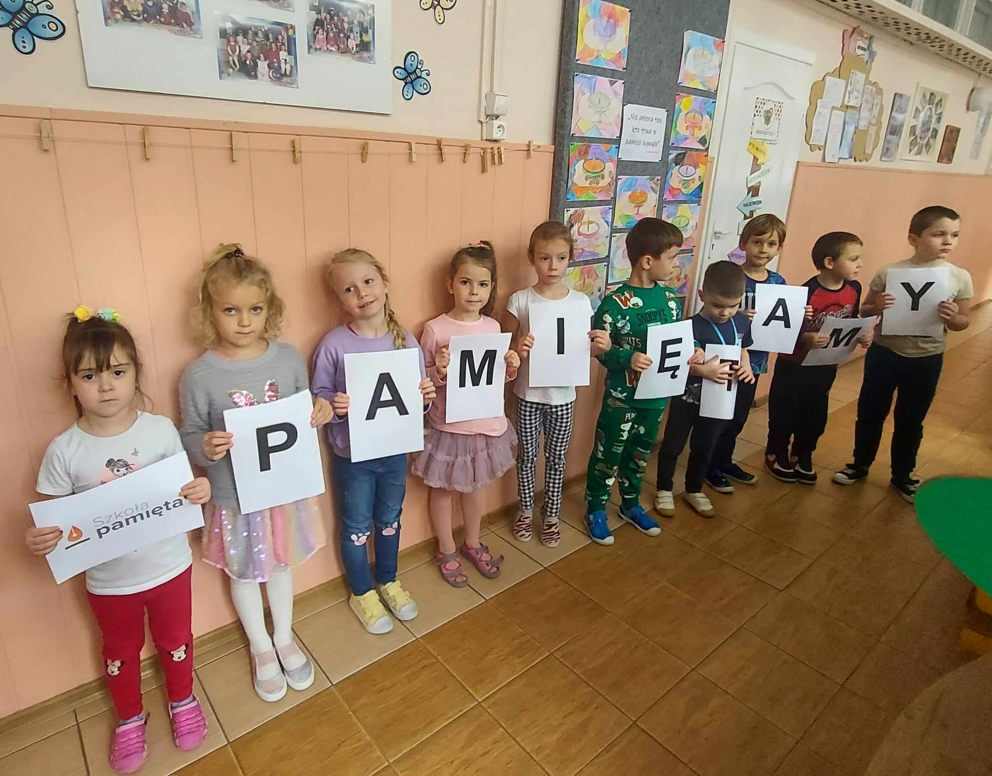 grupa dzieci stoi w przedszkolu dzieci trzymają w rękach napis pamiętamy