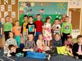 Grupa dzieci w wiosennych ubraniach stoi na tle kolorowej dekoracji z rowerem
