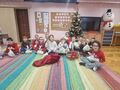 zdjęcie grupowe dzieci siedzą na dywanie przed nimi worek Mikołaja