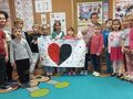 Grupa dzieci, trzymająca w rękach plakat z czarno- czerwonym sercem