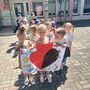 Grupa dzieci stoi przed przedszkolem trzymjąc w rękach plakat