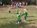 Dzieci w koszulkach z logo przedszkola biegną po wyznaczonej trasie