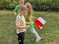 Dzieci w sportowych strojach stoją z flagami Polski