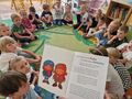 Dzieci siedzą na dywanie i słuchają opowiadania pt. jak Kuba i Helenka do powstania szli