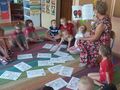 Dzieci wraz z nauczycielką oglądają ilustracje upamiętniające Powstanie Wielkopolskie