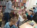 grupa dzieci ogląda książki na regałach