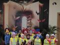 grupa dzieci w kamizelkach na tle fototapety z otwartą książką