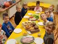 dzieci przy stoliku spożywają pieczywo różnego rodzaju oraz warzywa
