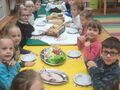 dzieci siedzą przy stole degustują różne rodzaje chleba oraz taca z pokrojonymi warzywami