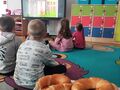 na pierwszym planie różnego rodzaju pieczywo w tle dzieci oglądające bajkę o uprawie zboża