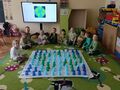 Dzieci na dywanie układają sylwetę Ziemi na macie do kodowania
