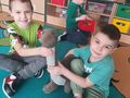 dwoje chłopców trzyma maskotkę dinozaura