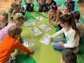 dzieci oglądają plansze z dinozaurami na dywanie
