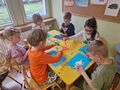 dzieci wykonują prace plastyczną z dinozaurem