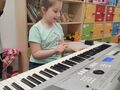 Uśmiechnięta dziewczynka gra na keyboardzie
