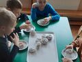 dzieci jedzą pączki posypane cukrem pudrem