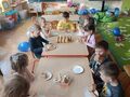 dzieci przy stoliku spożywają pączki z lukrem