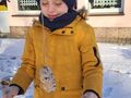 chłopiec ubrany w kurtkę i czapkę patrzy na kulkę z nasionkami zawieszoną na gałęzi