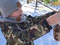 chłopiec zawiesza pokarm dla ptaków na krzaku