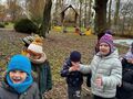 dzieci w ogrodzie przedszkolnym uzupełniają karmnik na drzewie